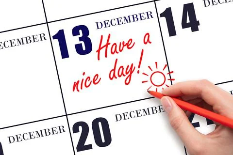 The hand writing the text Have a nice day and drawing the sun on the calendar Stock Photos