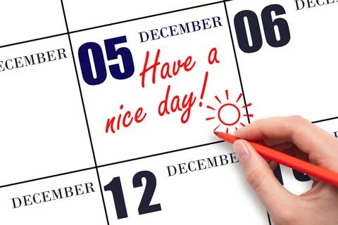 The hand writing the text Have a nice day and drawing the sun on the calendar Stock Photos