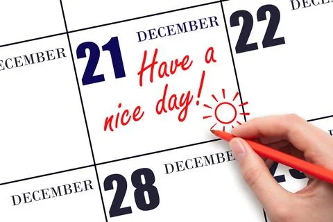 The hand writing the text Have a nice day and drawing the sun on the calendar Stock Photos