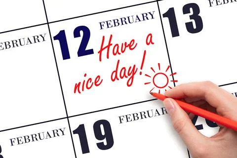 The hand writing the text Have a nice day and drawing the sun on the calendar Stock Photos