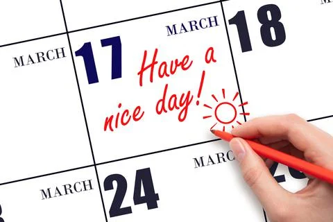 The hand writing the text Have a nice day and drawing the sun on the calendar Stock Photos