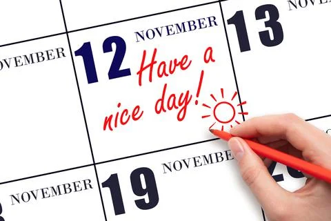 The hand writing the text Have a nice day and drawing the sun on the calendar Stock Photos