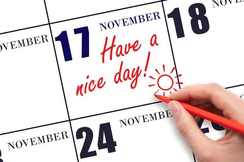 The hand writing the text Have a nice day and drawing the sun on the calendar Stock Photos