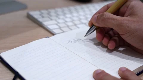 Hand Writing Today’s Plan and Marketing Meeting Notes in Notebook on Office Desk Stock Footage 332073437