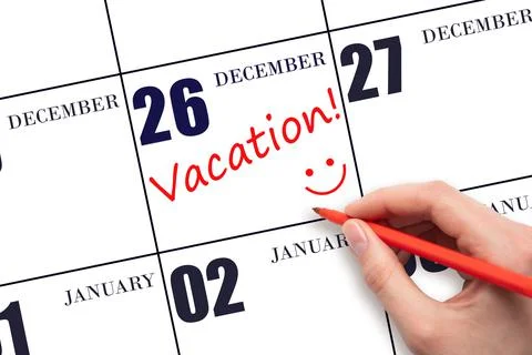 A hand writing a VACATION text and drawing a smiling face on a calendar date  Stock Photos