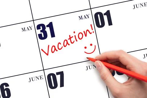A hand writing a VACATION text and drawing a smiling face on a calendar date  Stock Photos