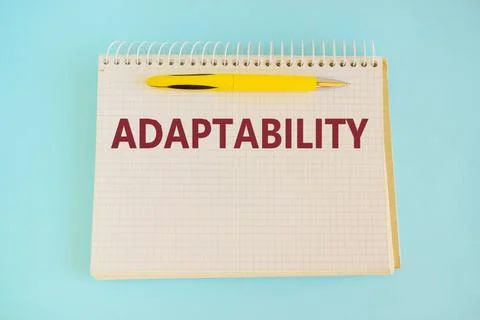 Hand writing the word Flexibility in notepad with yellow pen on blue backgrou Stock Photos