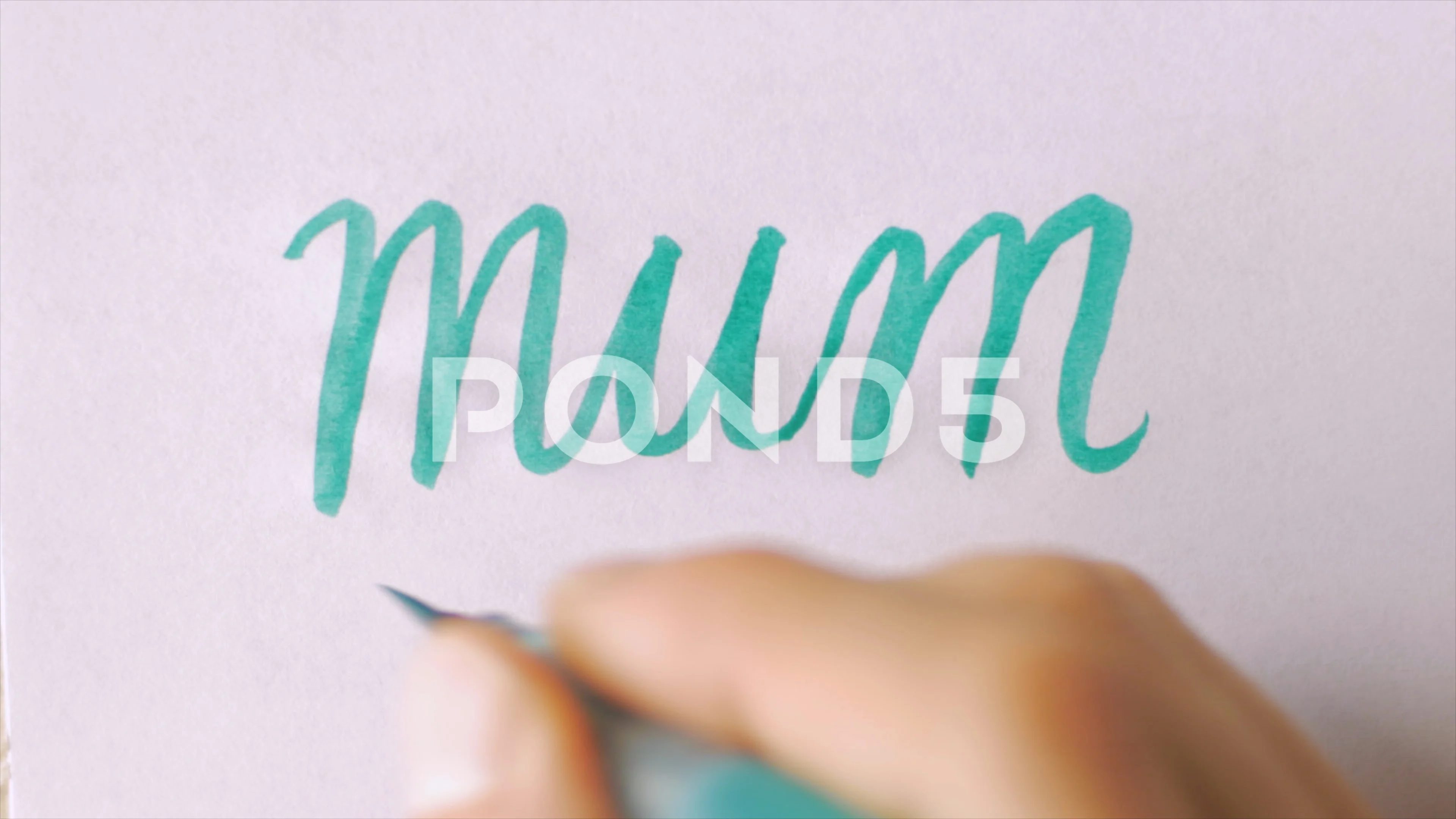 Hand writing the word MUM in an artistic way with a green brush pen