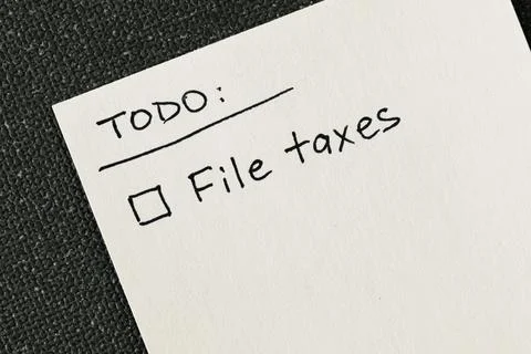 Hand written to-do list with 'File taxes' reminder on a white note Stock Photos