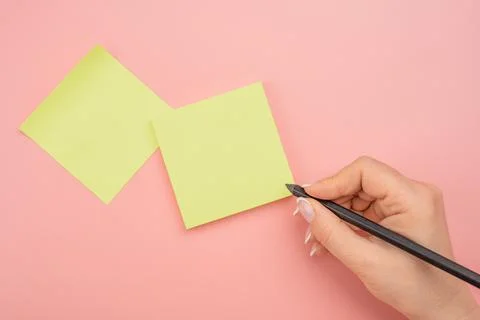 Hand written notes black pencil on yellow sticker. pink table background. wom Stock Photos