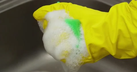 Hand in yellow gloves squeezes a sponge Stock Footage 235512310