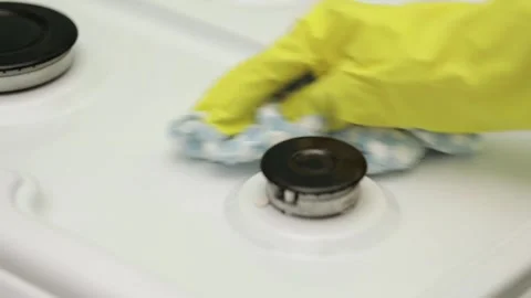 A hand in a yellow rubber glove washes a gas stove Video stock 246741959