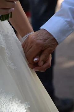 The hand of a young bride in the hands of a much older man Stock Photos