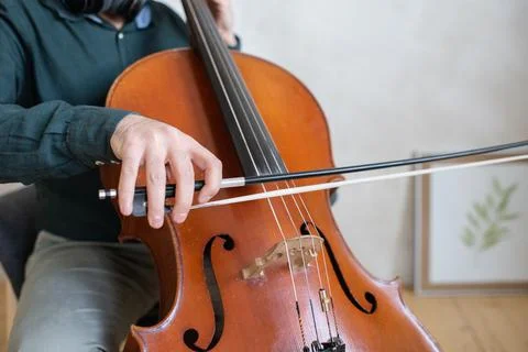 Hand of young cello player gliding fiddlestick across strings Foto stock