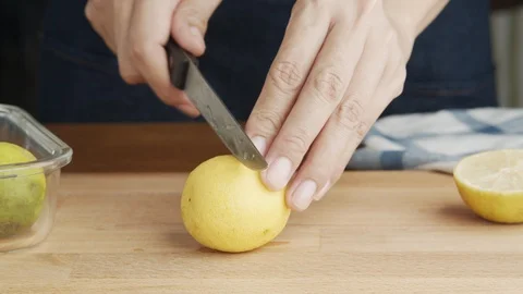 Hand of young chef using a knife  Sliced lemon on chopping board   in kitchen Stock Footage 115259247