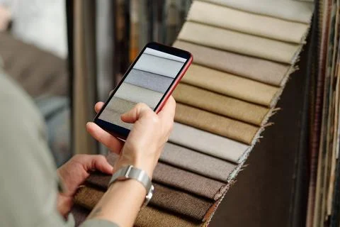 Hand of young female client taking photo of new samples of textile for furniture Foto stock