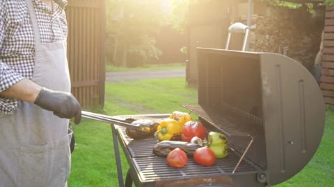 Hand of young man grilling vegetables on the barbecue plate with glowing coals Stock Footage 132826676