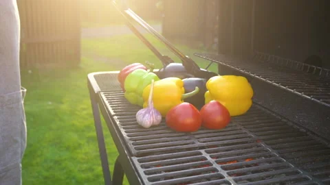 Hand of young man grilling vegetables on the barbecue plate with glowing coals Stock Footage 132826700