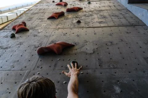 Hand of the young man on a hook of the artificial climbing wall Stock Photos