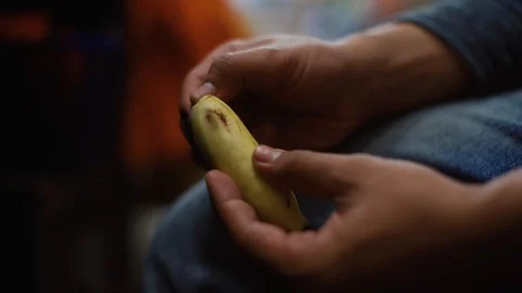 Hand of young man peeling small banana while sitting, and eat it. Stock Footage 93497636