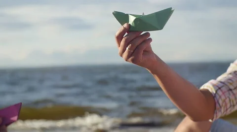  The hand of a young man playing with paper boat green. On the beach Stock Footage 60844018
