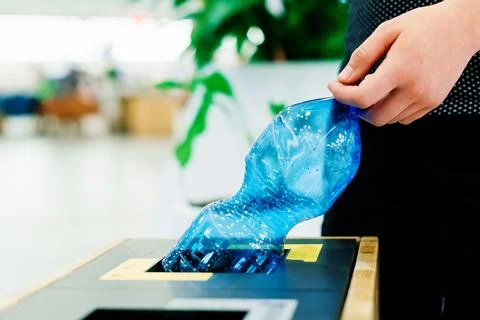 Hand of young man throwing plastic bottle in recycling trash bin Stock Photos
