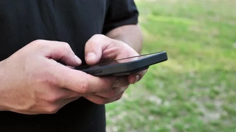 Hand of young man using mobile phone, writing message and browsing internet Stock Footage 334723421
