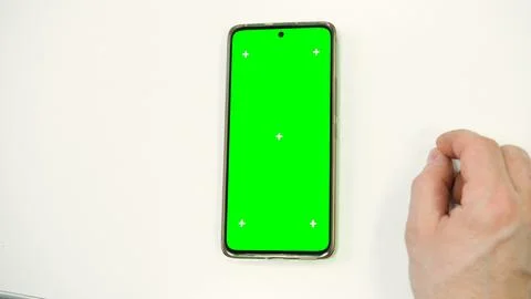 Hand of young man using mobile phone with green screen on white surface. Mobi Stock Photos