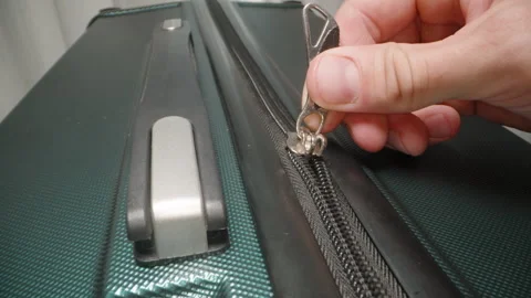 A Hand zips up the suitcase and secures the zipper pulls in the lock, finalizing Stock Footage 282300071