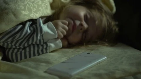 The hand of a zombie is interested in the phone of a sleeping little girl. Stock Footage 80477752