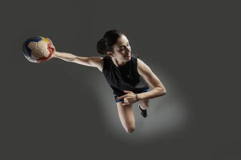 Handball player posing on gray background. Girl jumping with ball. Stock Photos