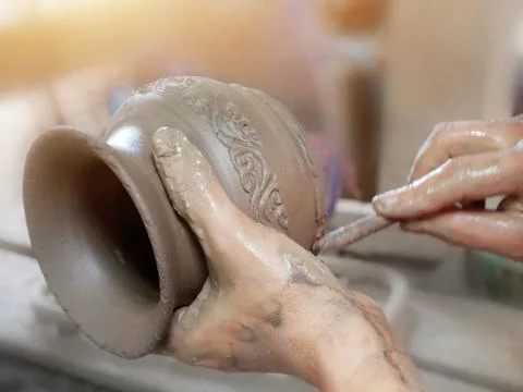 Handcraft artist making pattern on earthenware pottery. Stock Photos