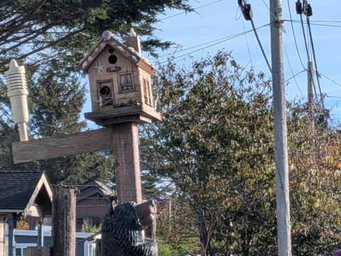 Handcrafted bird feeder shaped like a tiny house on a pole Stock Photos