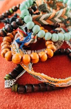 Handcrafted bracelets with wooden elements sit on a soft textile. It suggests Stock Photos