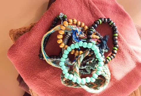 Handcrafted bracelets with wooden elements sit on a soft textile. It suggests Stock Photos