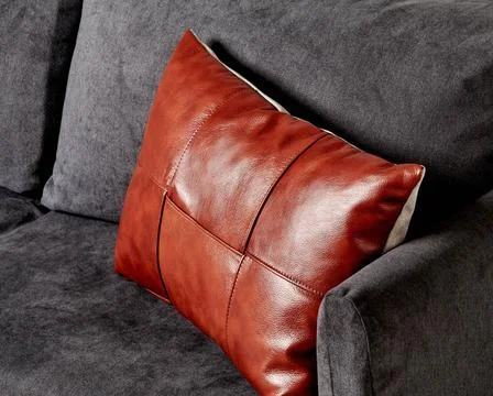 Handcrafted brown leather patchwork cushion on charcoal grey sofa Stylish ... Stock-Fotos