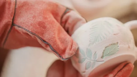 Handcrafted ceramic mug. Artisan hands delicately examine decorated pottery Vidéo 337371844
