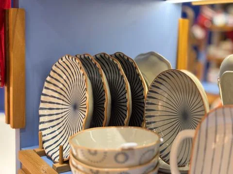 Handcrafted ceramic tableware displayed on a shelf in a store or market Stock Photos