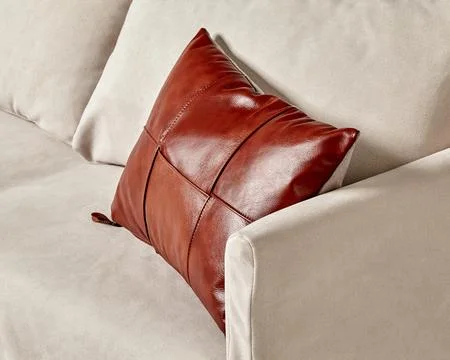 Handcrafted glossy brown leather patchwork cushion on light grey sofa Photos