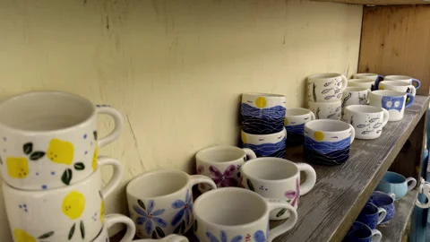 Handcrafted Painted Ceramic Mugs Displayed on Wooden Shelves Stock Footage 347909535