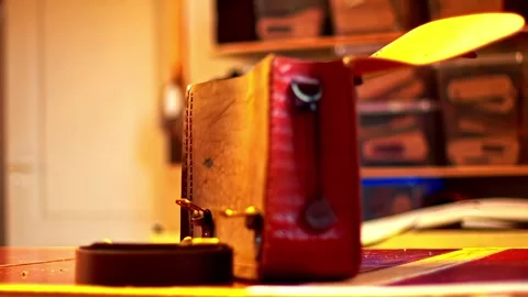 Handcrafted red and tan leather satchel with an open flap resting on a workbench Stock Footage 332734919