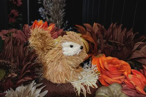 Handcrafted straw squirrel decoration surrounded by autumn flowers and pump.. Stock Photos