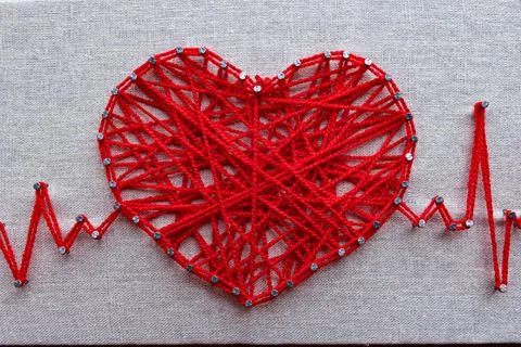 Handcrafted string art in shape of heart with cardio pulse lines made of red  Stock Photos