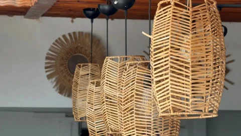Handcrafted wicker lamps hanging in a rustic interior setting, creating a w.. Stock Footage 330897616