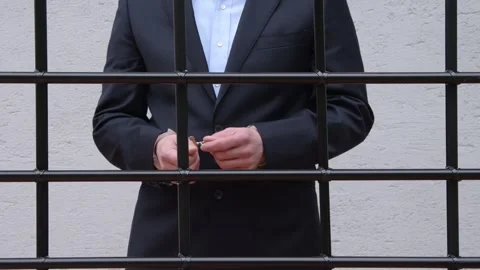 Handcuffed man behind bars in a cell, imprisonment or trial and sentence. Stock Footage 289305791