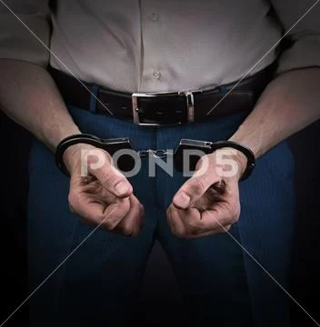 Handcuffed offender against a dark background Stock Photos