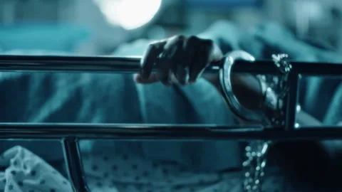 Handcuffed prisoner grabbing bed rail in a prison hospital Stock Footage 331604481