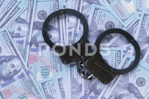 Handcuffs against the background of hundred-dollar bills Stock Photos