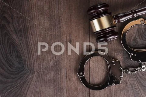 Handcuffs and judge gavel on wooden background Stock Photos