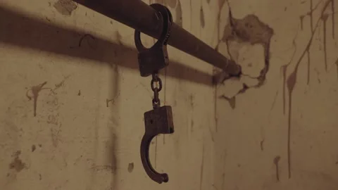 The handcuffs chained to a pipe in an old abandoned building or horror house Stock Footage 238661628